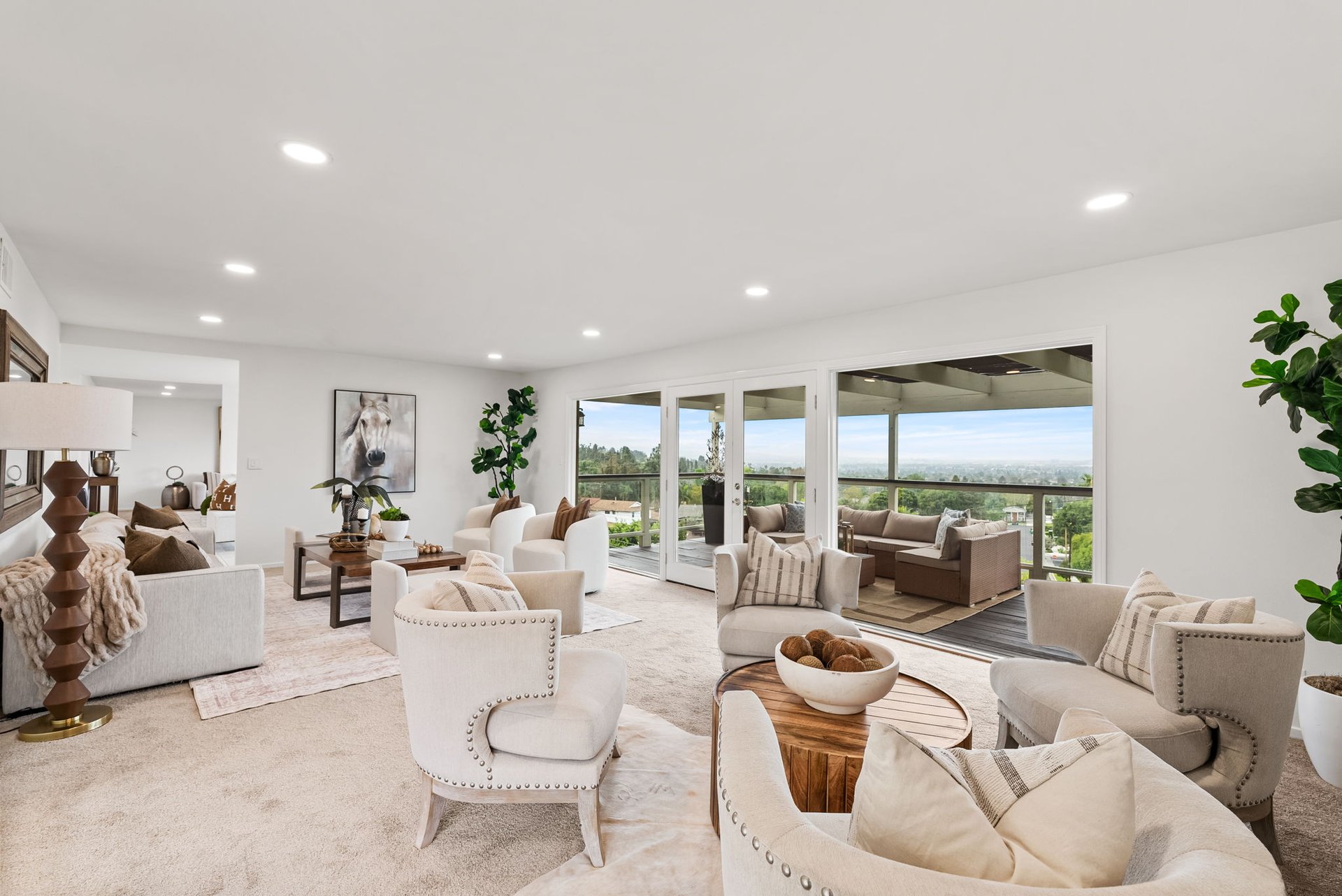 Staged living room with cream seating and wide glass doors opening to a covered patio.