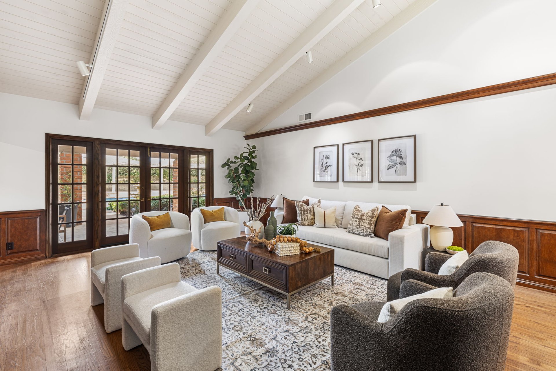 Living room with a vaulted beamed ceiling, dark wood French doors, and a furnished seating area.
