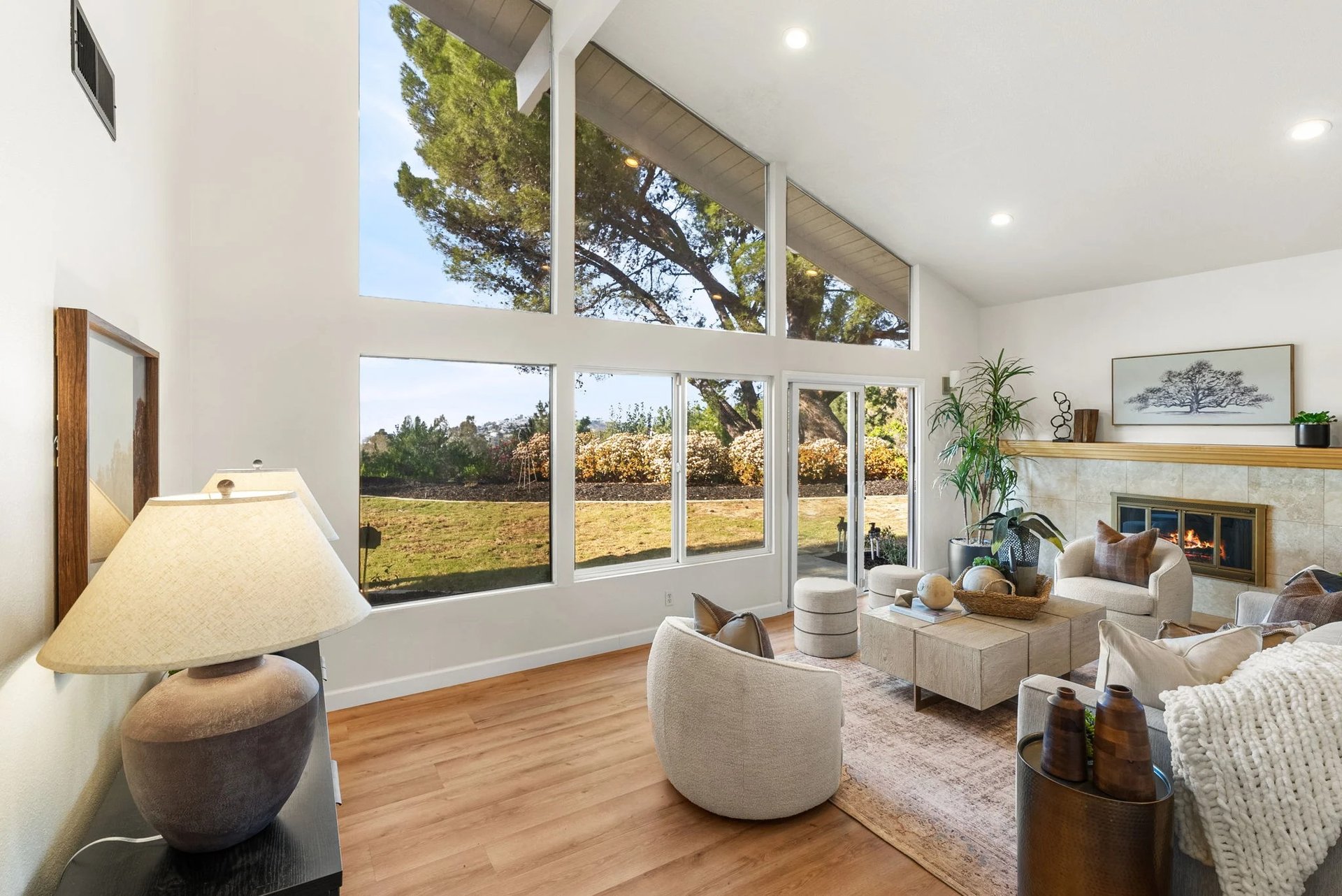 Living room with vaulted ceilings, expansive yard-facing windows, and a fireplace.