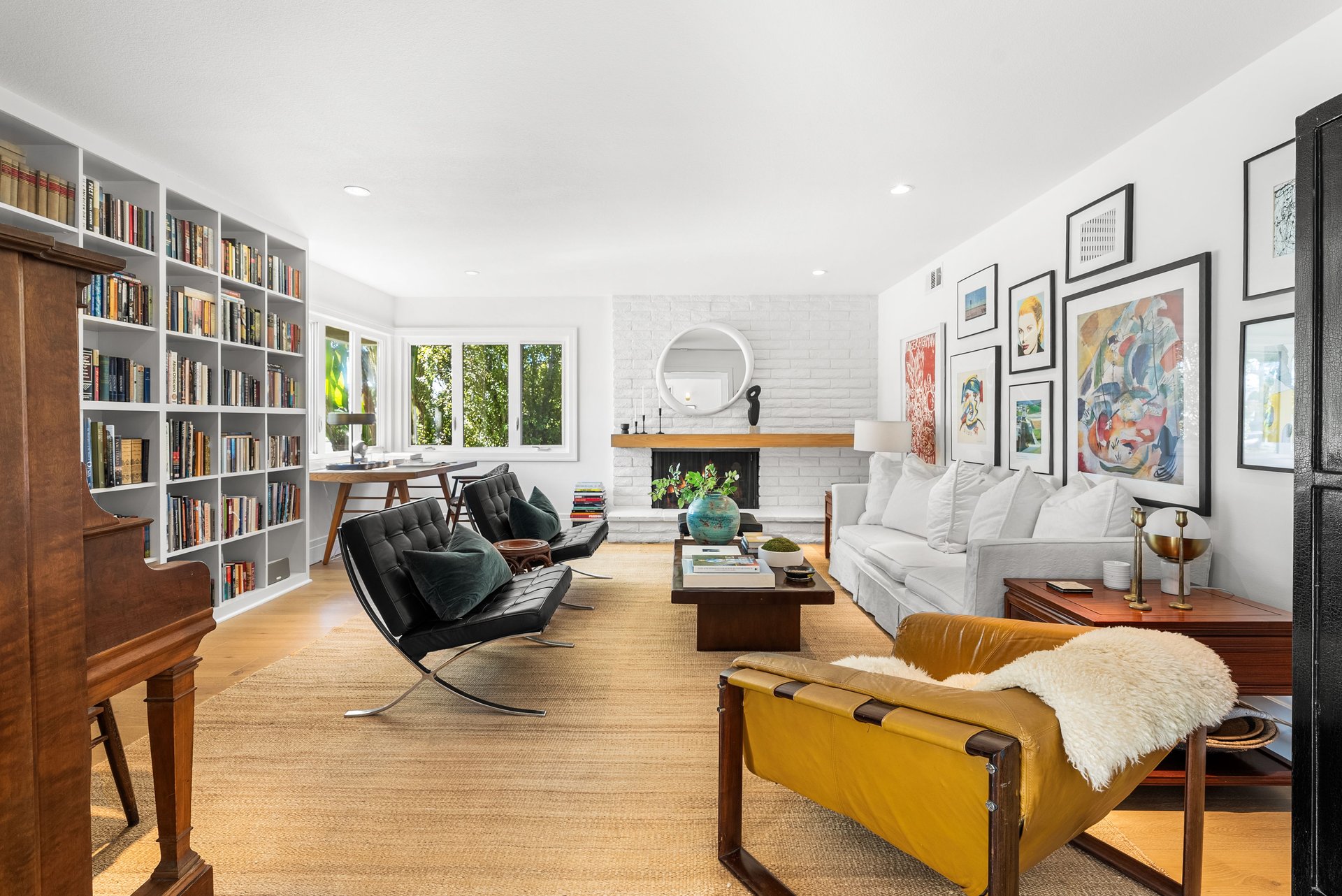 Living room with built-in bookshelves, a white brick fireplace, and a gallery wall.