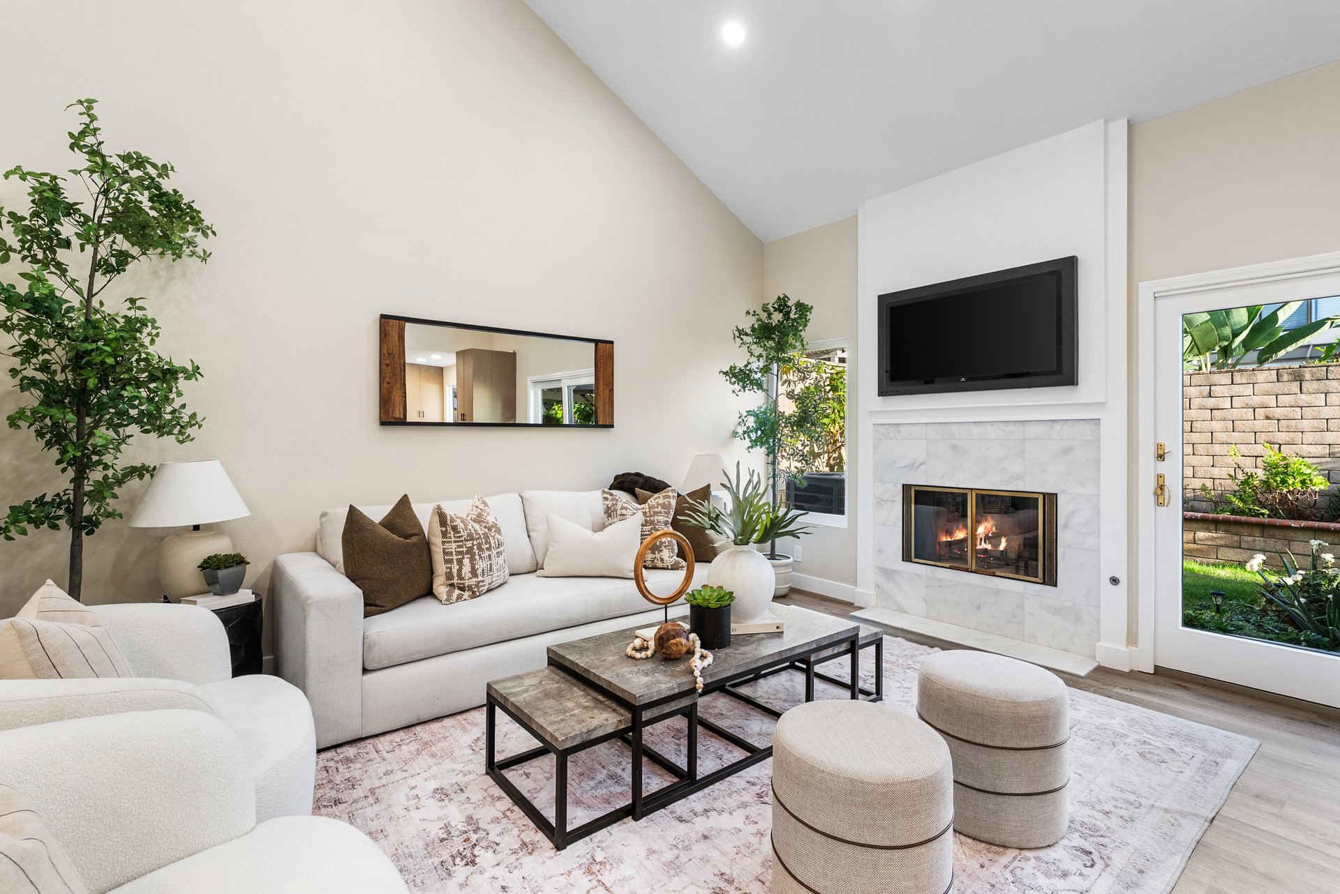 Living room with a vaulted ceiling, marble fireplace, and pale sectional seating.