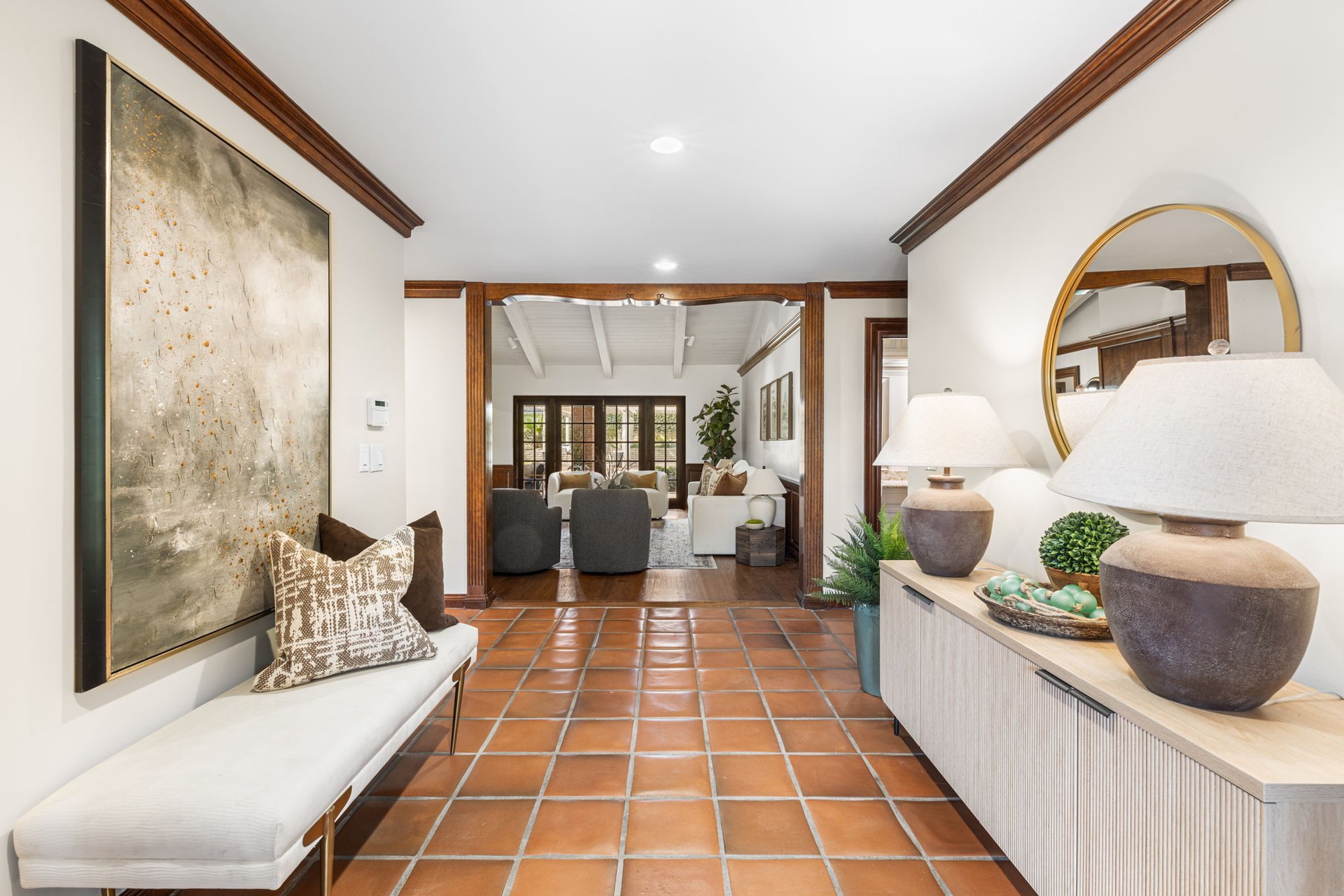 Furnished entry hall with terracotta tile floors and dark wood trim, opening into a living room.
